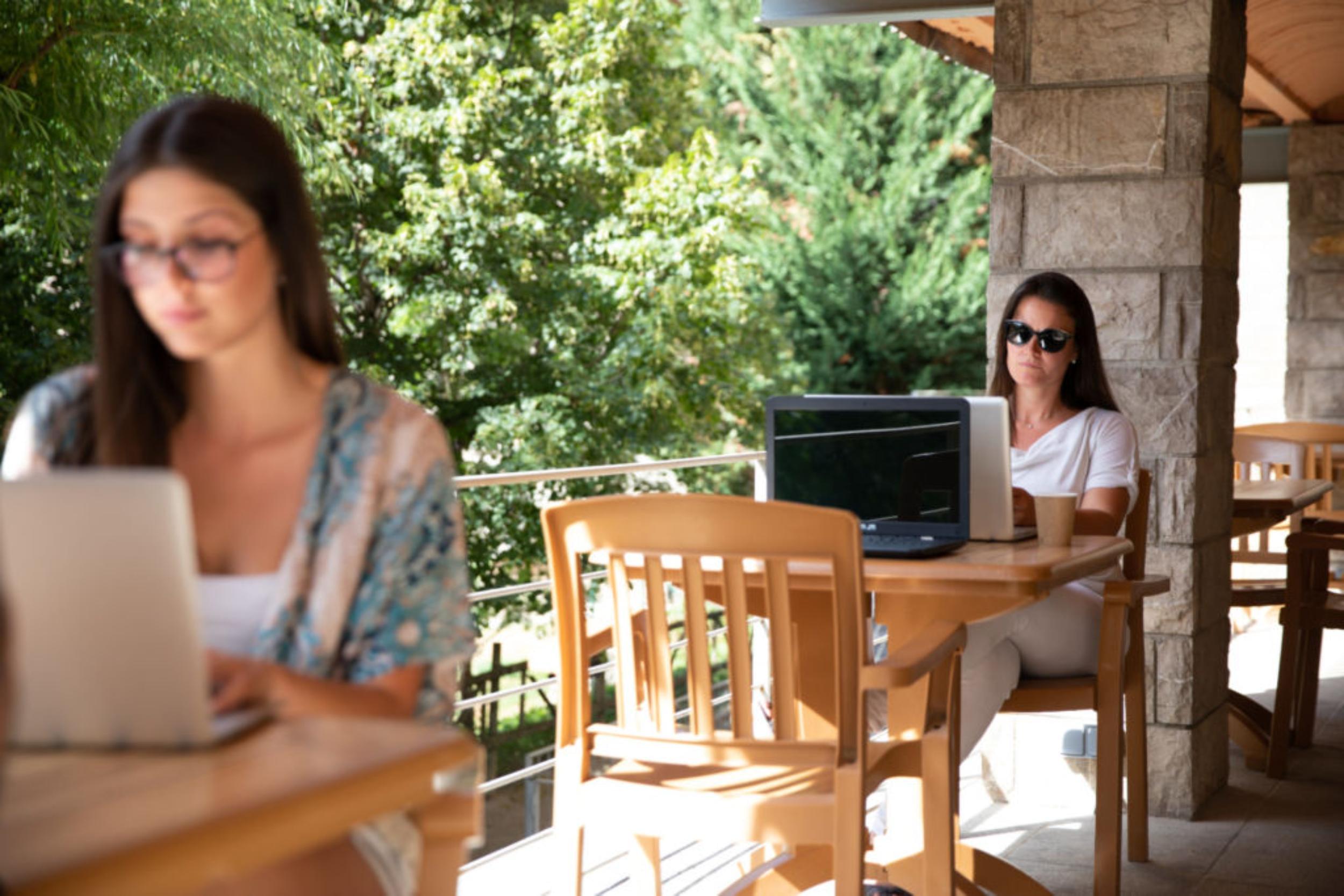 Noies treballant al coworking des de la terrassa