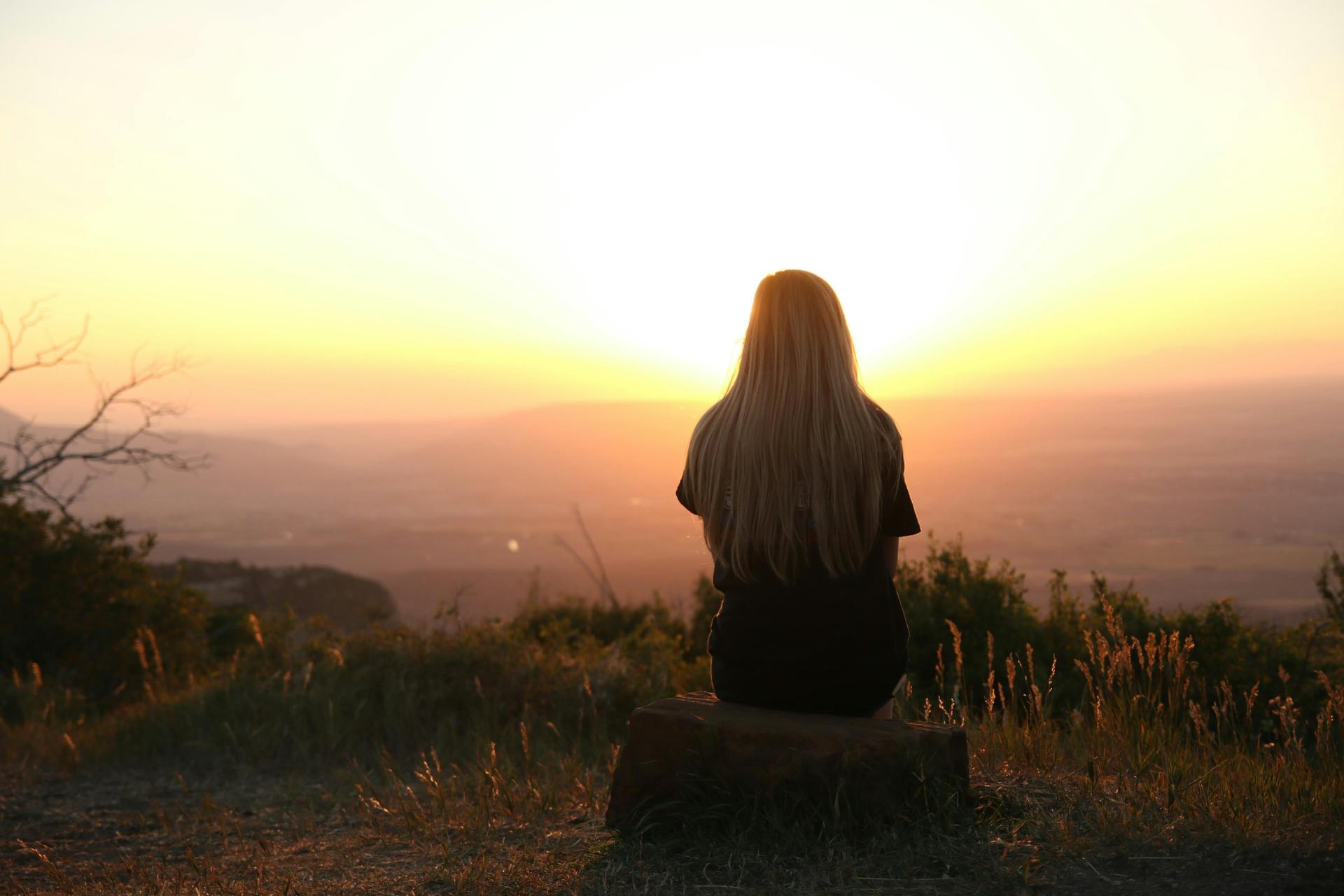 Noia veient una posta de sol